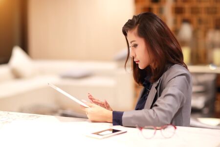 working and charming woman with glasses using tablet and cell phone (work from home concept)の写真素材