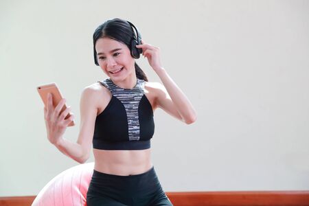 young healthy and sporty woman listen music from cell phone in gymの写真素材