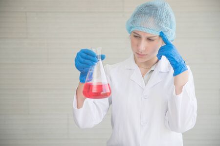 scientist woman with equipment and laboratory glassware holding chemical liquid and checking result using as science research backgroundの写真素材