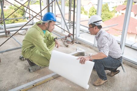 engineer people working and discussing with architecture or blueprint at construction siteの写真素材