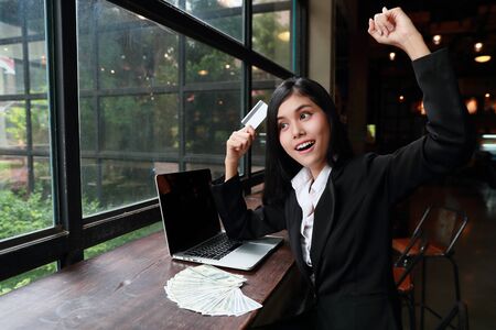 successful and happy businesswoman with computer holding credit card and say yeahの写真素材