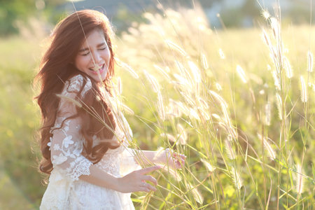 portrait of beautiful woman having a happy time and enjoying among grass field in natureの写真素材