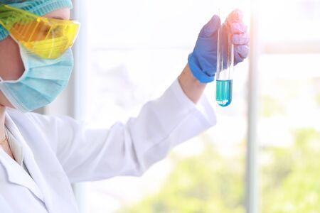 scientist woman with equipment and laboratory glassware holding chemical liquid and checking result using as science research backgroundの写真素材