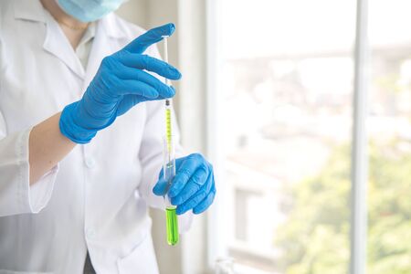 scientist woman with equipment and laboratory glassware holding chemical liquid and checking result using as science research backgroundの写真素材