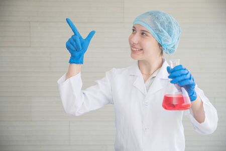 scientist woman with equipment and laboratory glassware holding chemical liquid and checking result using as science research backgroundの写真素材