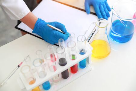 scientist woman with equipment and laboratory glassware holding chemical liquid and checking result using as science research backgroundの写真素材