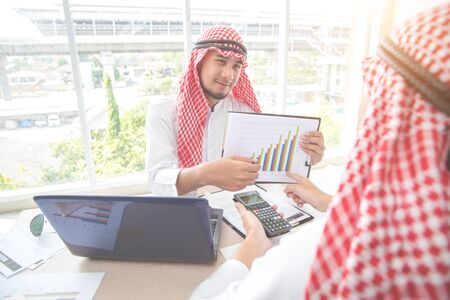 arab saudi businessman working and discussing with graph and calculator in officeの写真素材