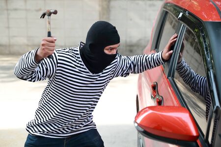 thief try to break into car with hammer (theft concept)の写真素材