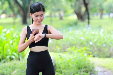 sport girl holding smart phone and checking smart watchの写真素材