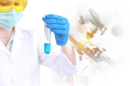 Young scientist holding test tubes with microscope or laboratory double exposure backgroundの写真素材
