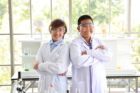happy kids making science experiments and confident in themselves and crossing one's arm (education and scientist concept)の写真素材