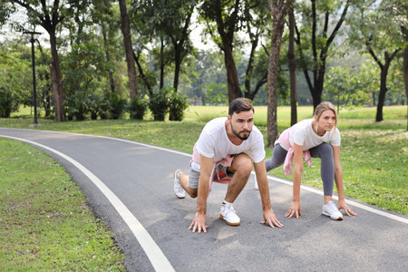 a runner caucasian couple is at starter for jogging in the park during summer season with smile...