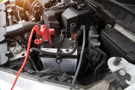 Mechanic charging old car with electricity trough jumper cables