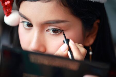 young asian santa girl applying eye shadow on beautiful faceの写真素材