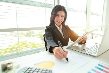 businesswoman using tablet and laptop computer while working on company summary report with graphの写真素材