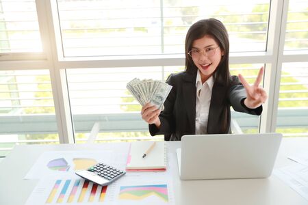 businesswoman showing company summary report and graph with money on handsの写真素材