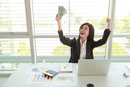businesswoman showing company summary report and graph with money on handsの写真素材