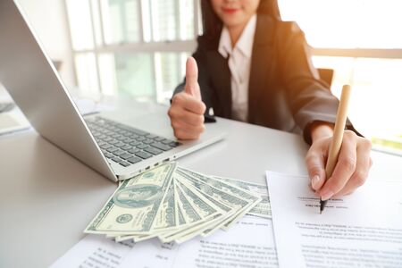 businesswoman signing contract and showing thumb up with moneyの写真素材