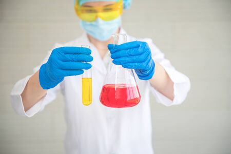 scientist woman with equipment and laboratory glassware holding chemical liquid and checking result using as science research backgroundの写真素材