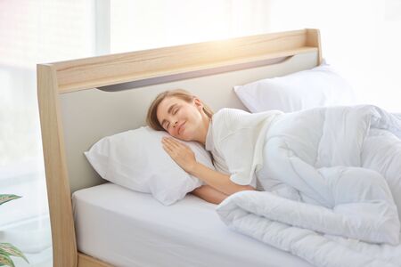young beautiful woman sleeping in bed with relaxation and happy face in the morningの写真素材