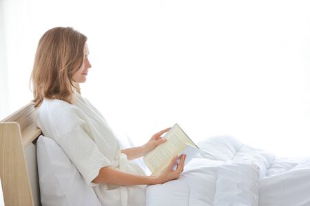 healthy and beautiful girl reading book on bed with happy and beautiful faceの写真素材