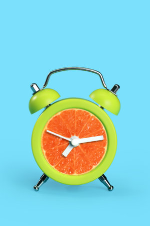orange in time clock on blue pastel deskの写真素材