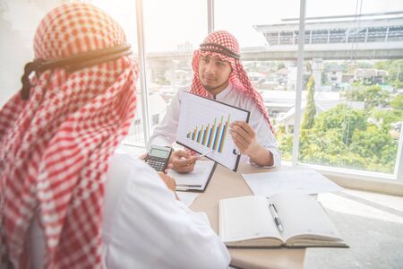 arab saudi businessman working and discussing with graph and calculator in officeの写真素材