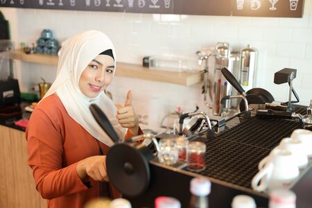 young muslim barista girl making coffee and show thumb up meaning of business successの写真素材