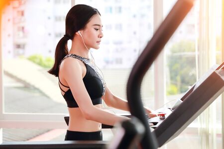 young healthy sport girl walking and listening music on exercise machine in gym (workout concept)の写真素材