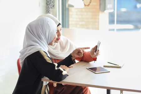 young muslim businesswomen discussion and shopping and online payment by using cell phone with tablet on wood deskの写真素材