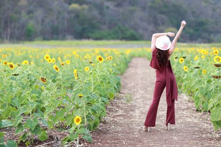 Portrait of beautiful woman having a happy time and enjoying among sunflower field in natureの写真素材