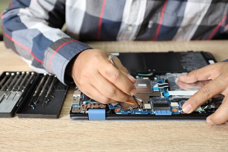 technician man using screwdriver to fix or upgrade laptop computerの写真素材