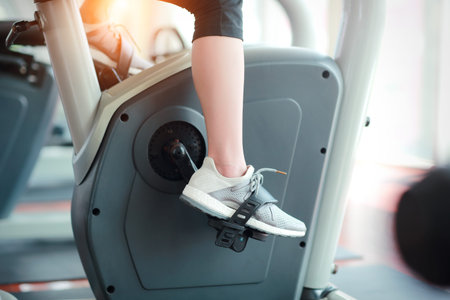 portrait of young healthy and sporty woman feet bicycling on exercise machine in gym