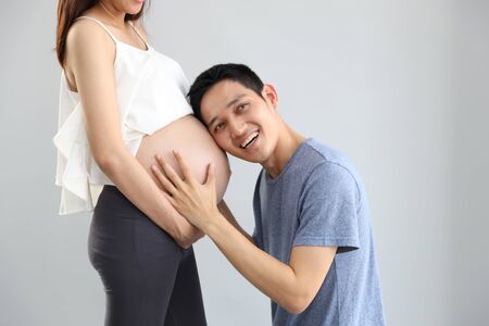 husband listening young pregnant belly wife with smile and loveの写真素材
