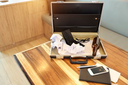 business bag with empty wallet, alcohol bottle and paper garbage on wood tableの写真素材