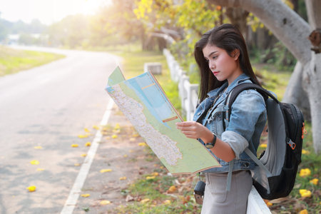 Young asian traveler searching direction on location map while traveling during holiday vacation