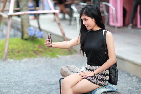 Young asian traveler using smart phone and do self portrait while traveling during holiday vacation