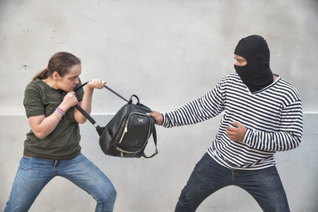 thief stealing bag from walking woman on street with knife in hand (theft concept)