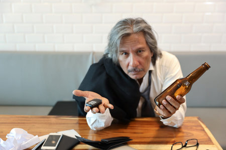close up shot senior asian businessman, white hair and black suit showing car key and empty alcohol...