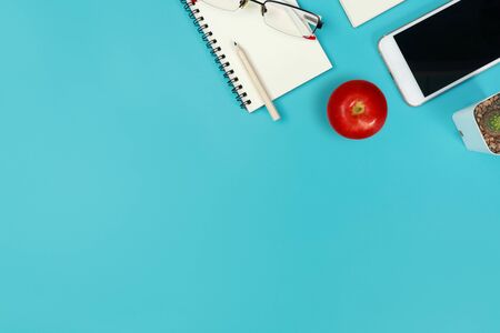 top view blue pastel office desk with computer, office supplies and appleの写真素材