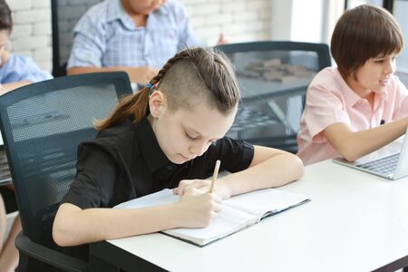 smart school kid writing in class (education concept)