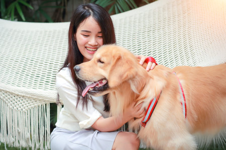 young and cute asian women lying in a hammock and playing with dog during holiday