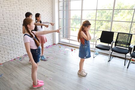 group of jealous school kids pointing to poor cute girl while she crying in classの写真素材