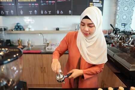 young muslim barista woman making coffee with concentration faceの写真素材