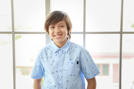 portrait of cute little student boy standing in blue shirt with happy smiling face