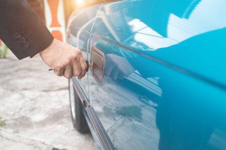 businessman hand unlock or lock old car door with keyの写真素材