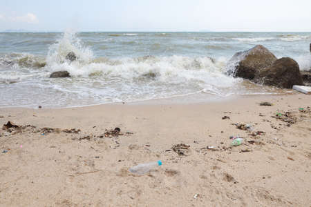 angle view image of empty plastic water bottle on dirty beach filled with plastic pollution, garbage and waste on dirty sandy beachの写真素材