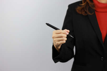 Business woman wearing black and red business suit uniform holding pen and drawing something with confident on white background studio (business growth advertisement concept)の写真素材