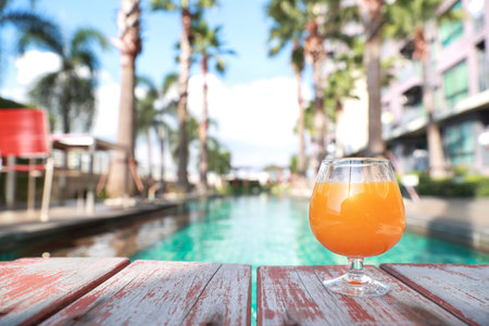 orange juice on swimming pool with palm tree and copy space, using for background