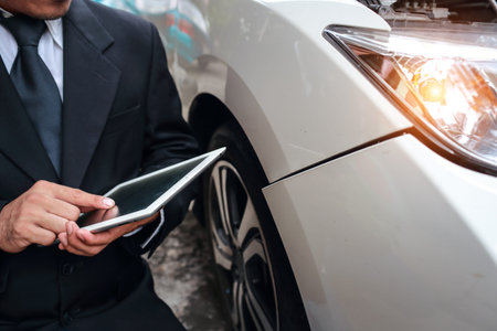 Insurance agent using tablet for insurance claim with damaged car on accident